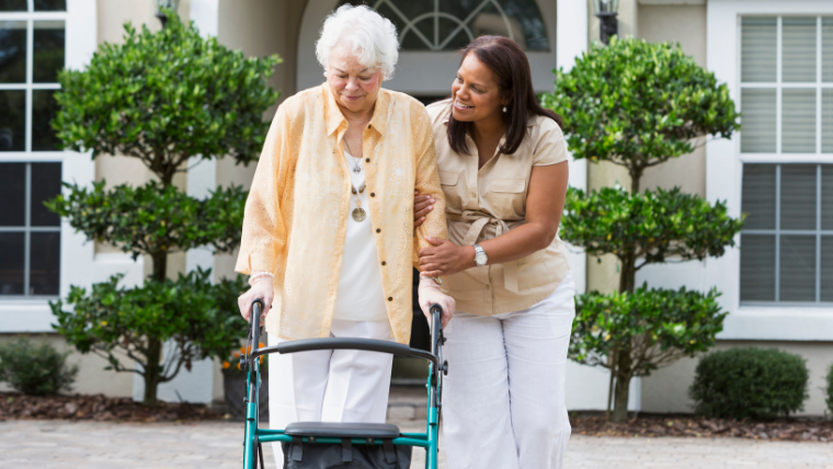 Professional NEMT driver assisting an elderly patient from their front door to the vehicle in South Florida.