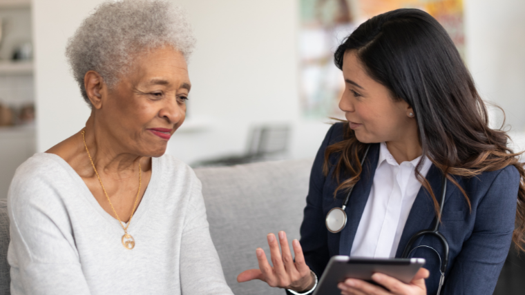Caregiver helping elderly woman prepare for a medical transport ride at home